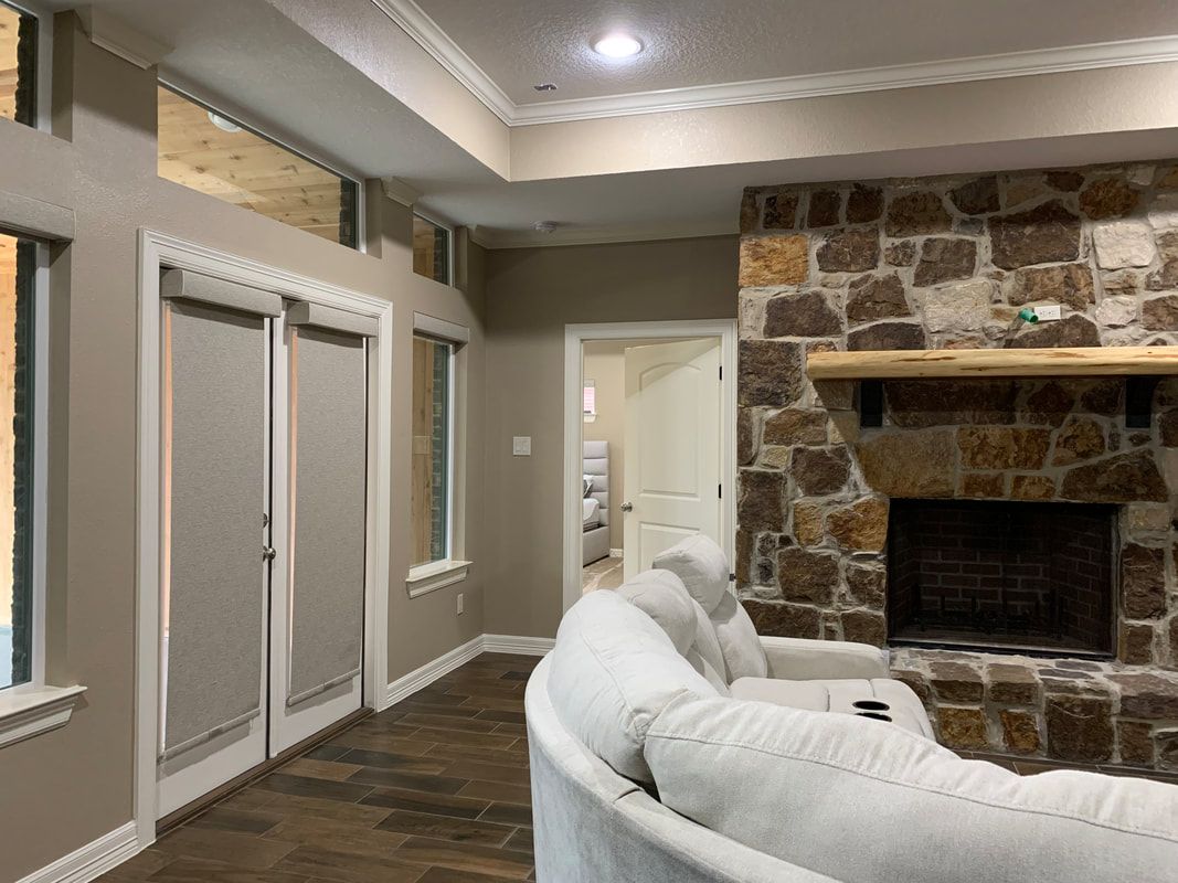 Living room with stone fireplace, white couch, doorway, and windows with light gray walls.