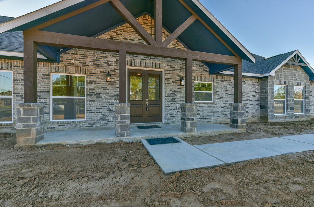 Ranch-style house with gray brick facade, covered porch, and concrete walkway.