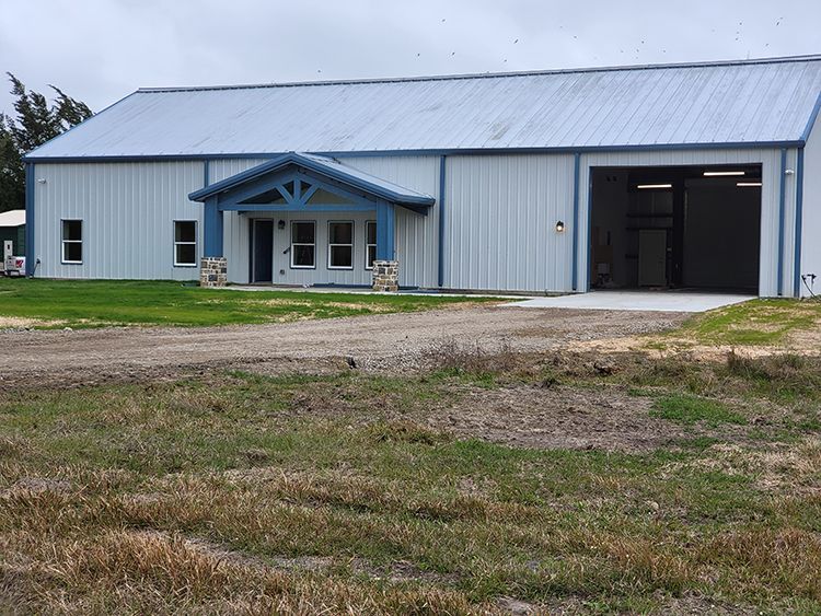 Light blue metal building with an open garage door and small porch.