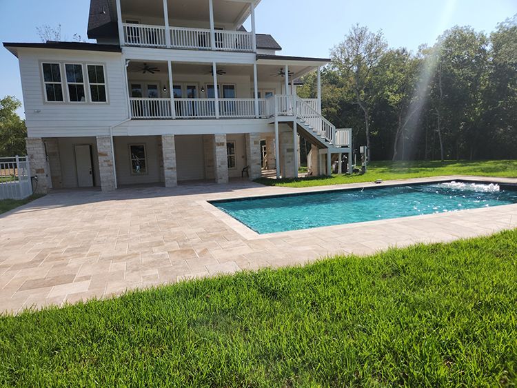 White house with a pool and green lawn; sun shining in the background.