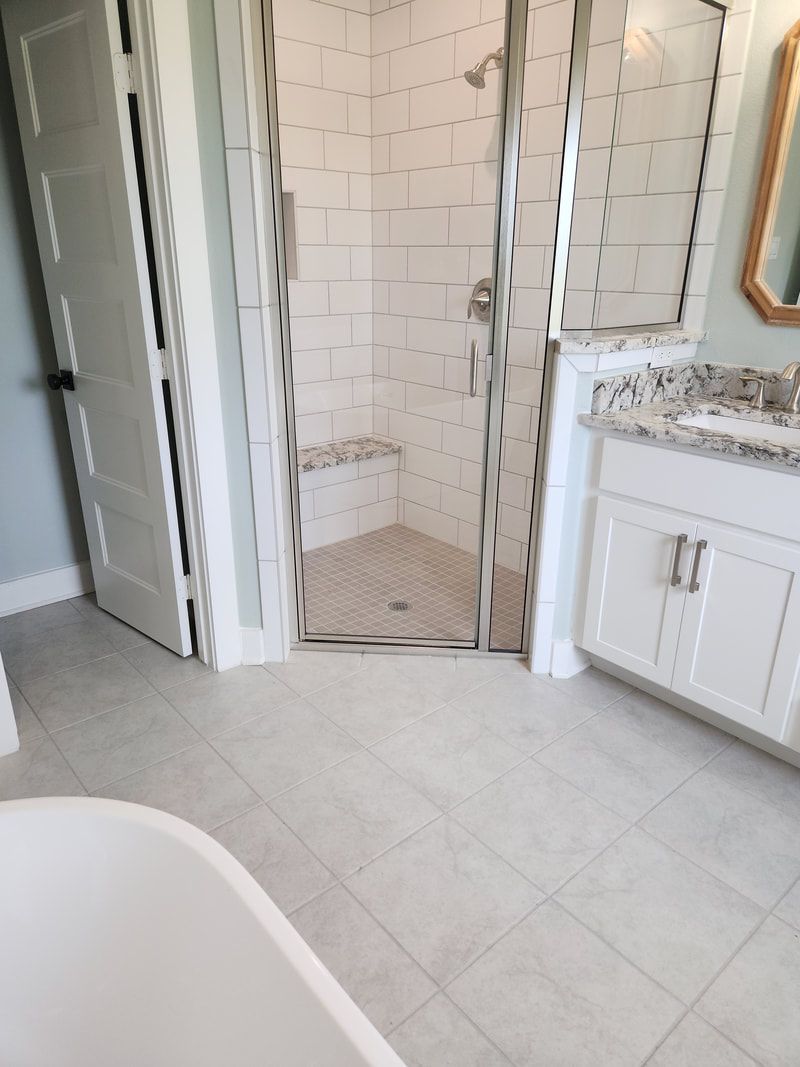 Bathroom with a shower, vanity, white tile, and a bathtub.
