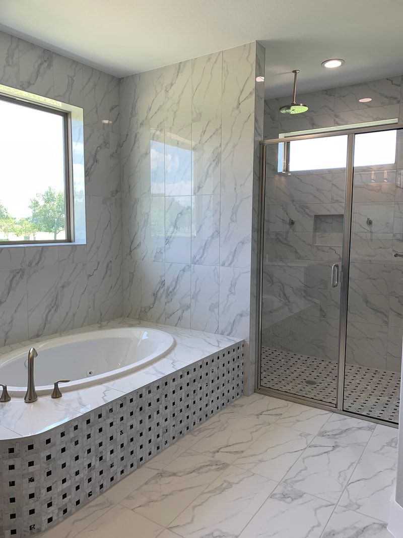 Spacious bathroom with marble tile, a soaking tub, and a glass-enclosed shower.