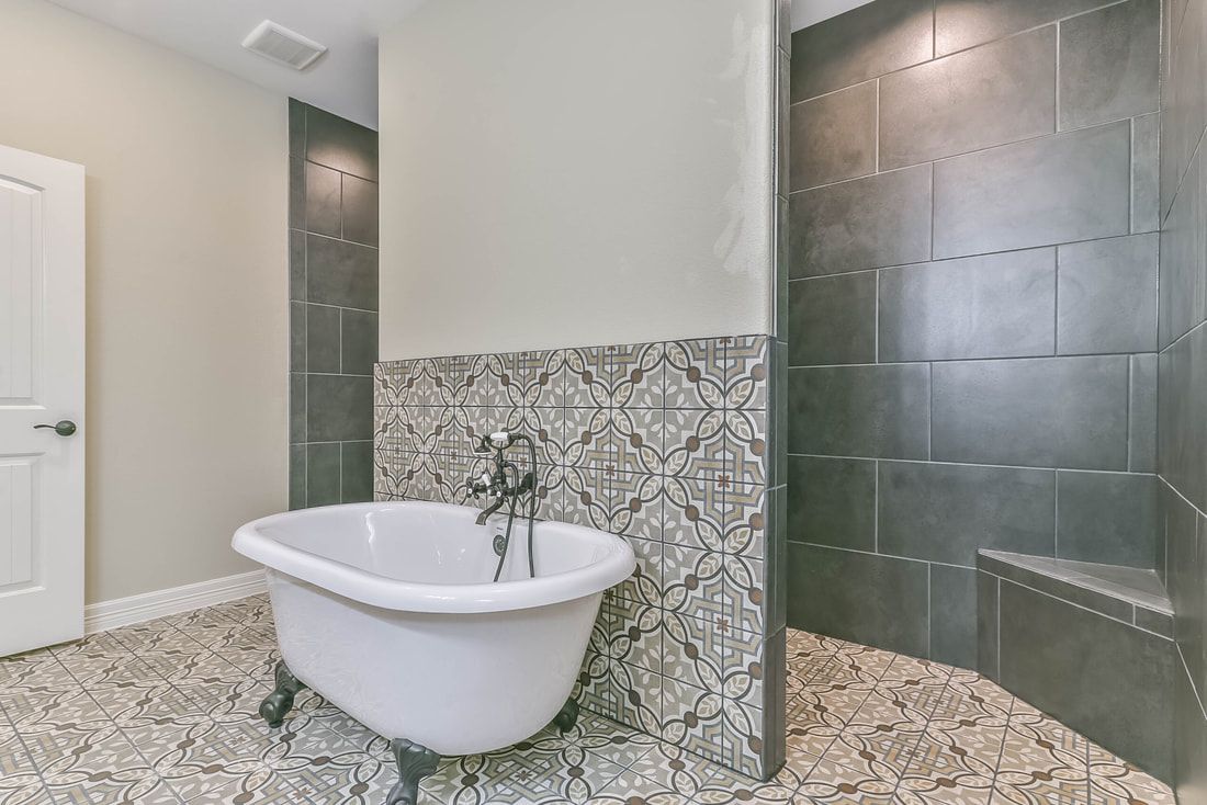 Bathroom with white clawfoot tub, patterned tile, and dark shower.