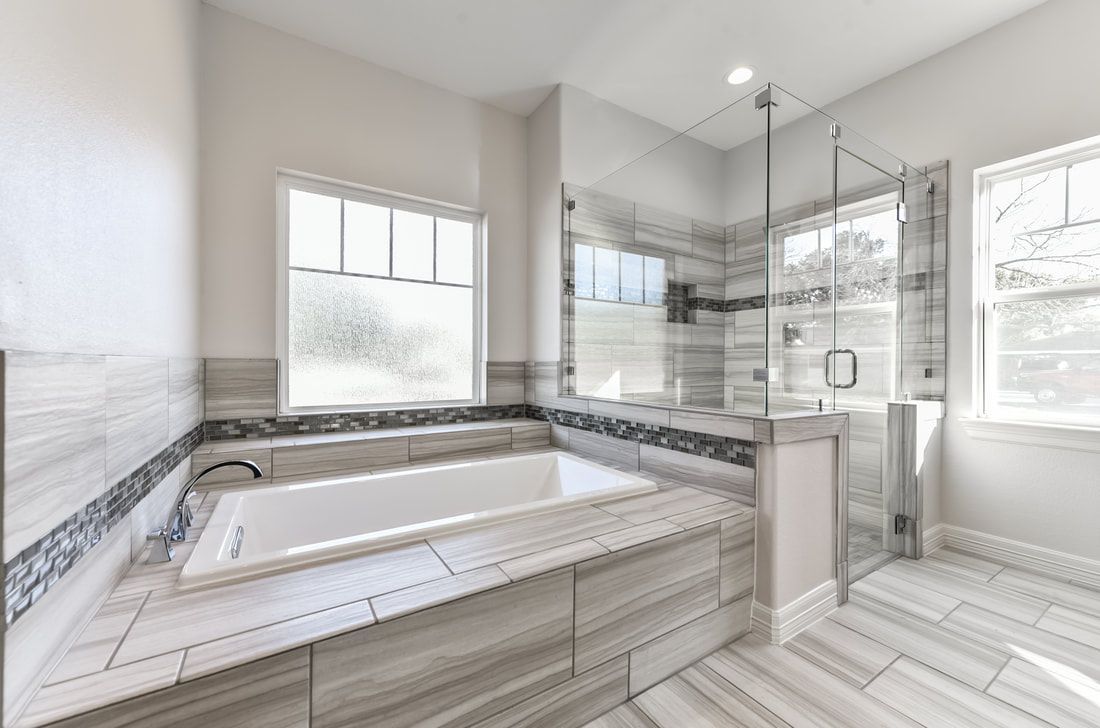 Modern bathroom with a white bathtub, glass shower, and tiled walls and floors.
