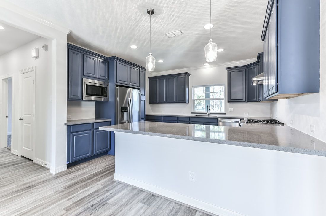 Modern kitchen with blue cabinets, stainless steel appliances, and a white island.
