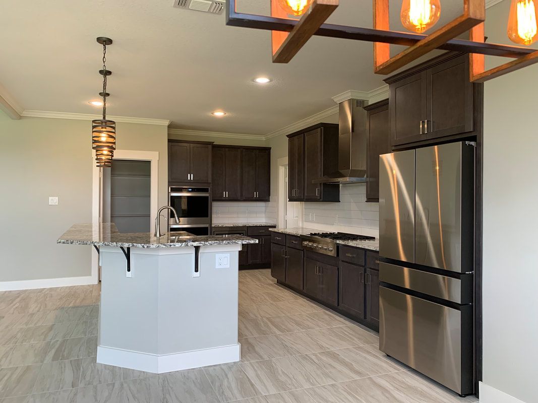 Modern kitchen with dark brown cabinets, stainless steel appliances, and gray island.