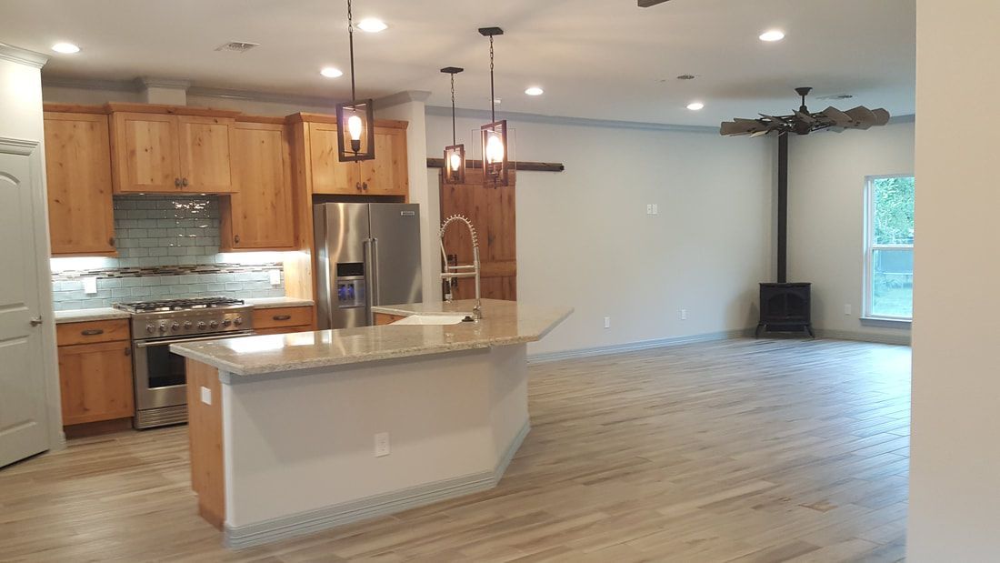 Open kitchen with wood cabinets, island, stainless steel appliances, and a wood floor.
