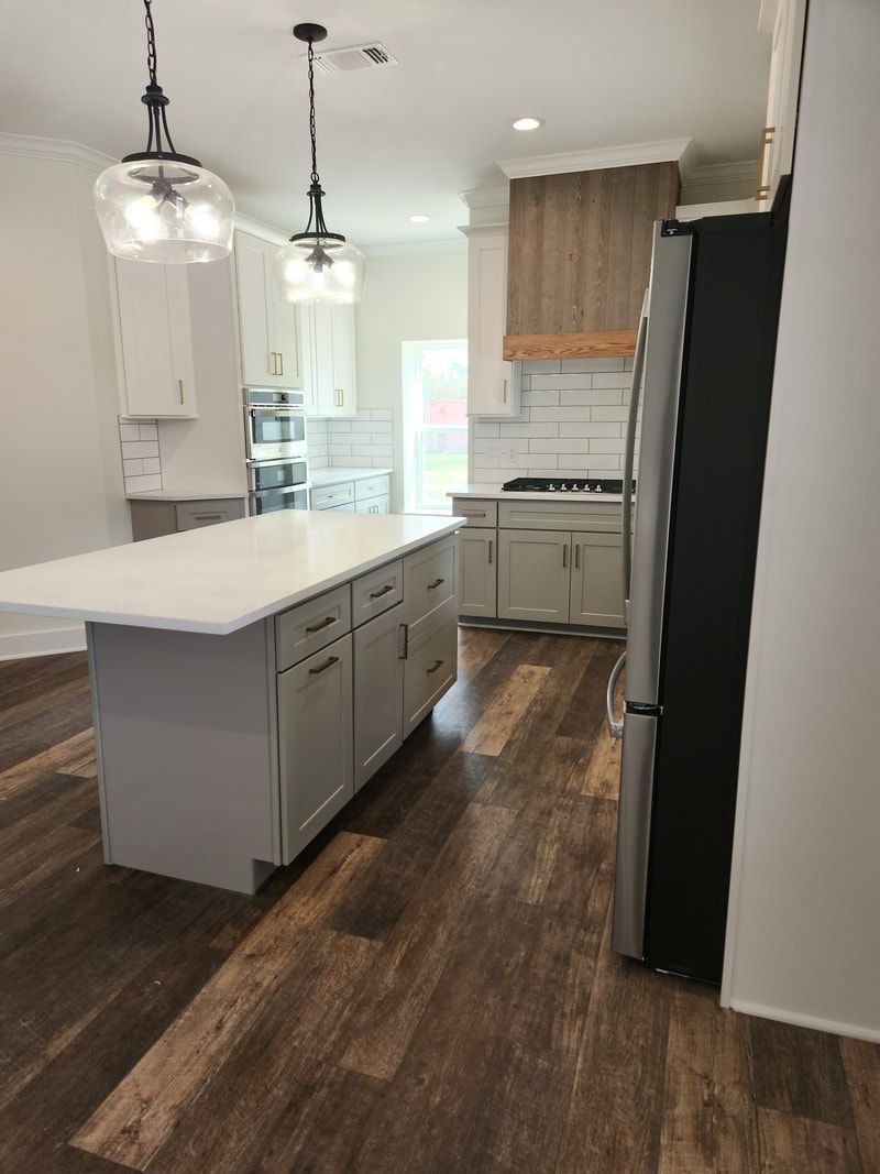 Modern kitchen with gray cabinets, white countertops, and wood-look flooring.