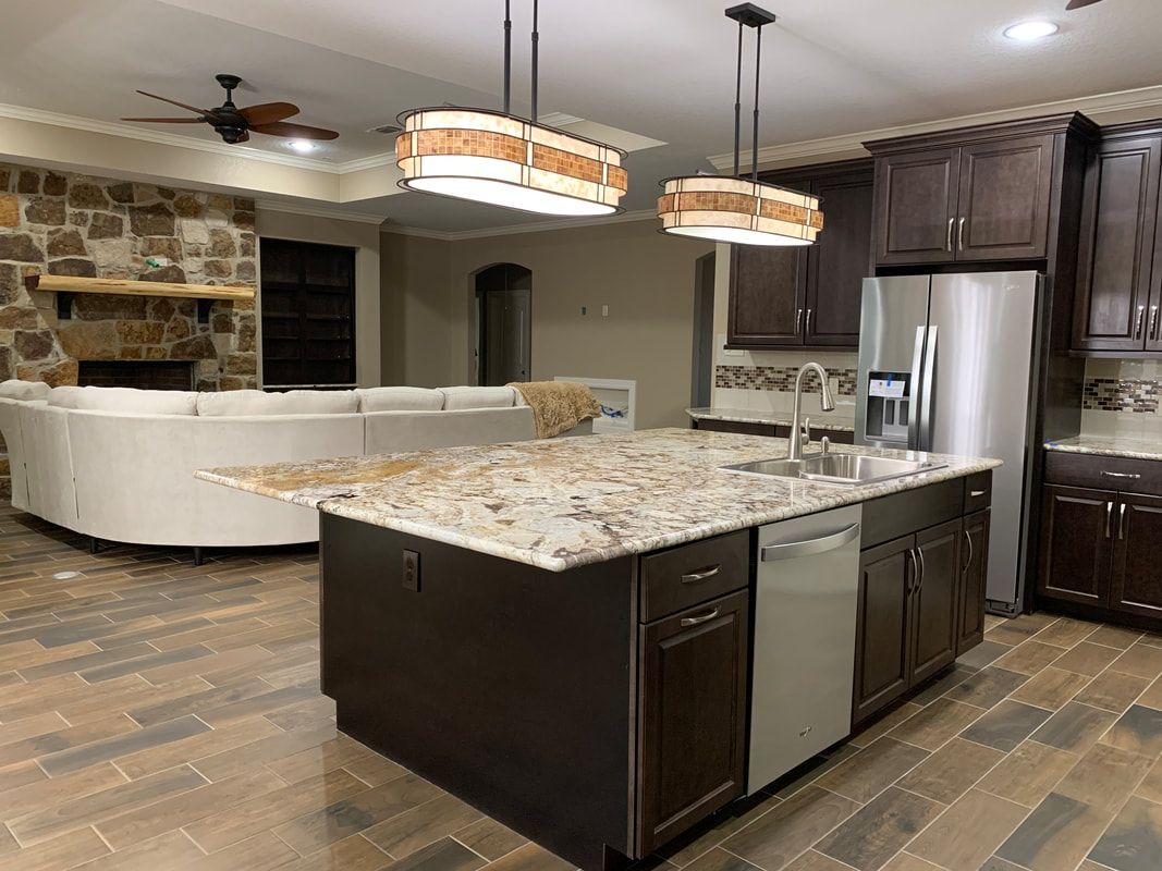 Kitchen with island, dark brown cabinets, granite countertops, and stainless steel appliances.