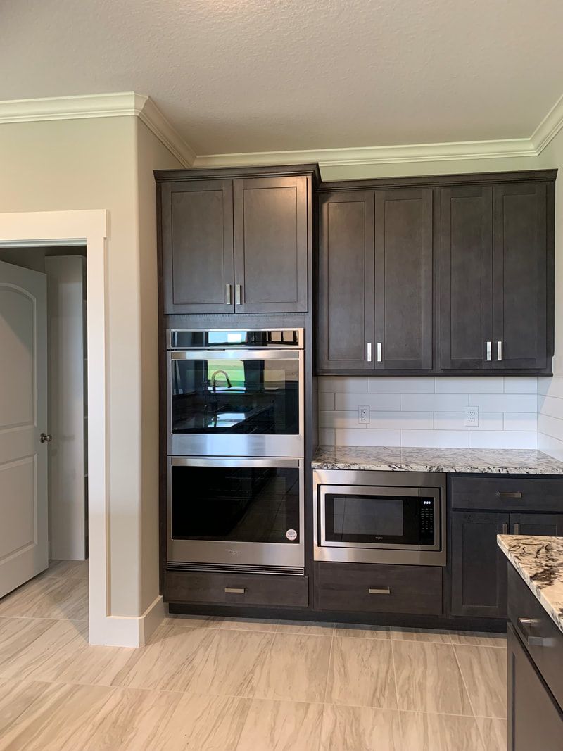 Built-in kitchen appliances: double oven, microwave, and cabinets in a gray and white kitchen.