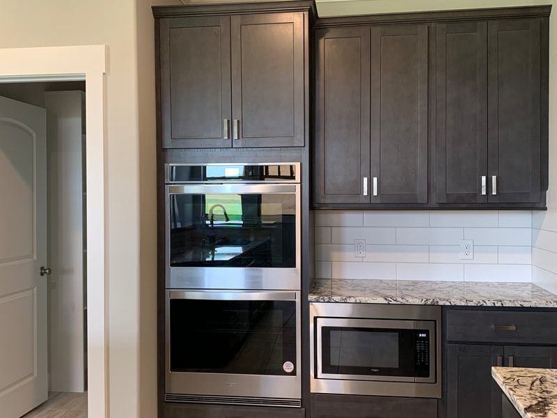 Built-in kitchen appliances: gray cabinets, stainless steel oven, microwave, and granite countertop.