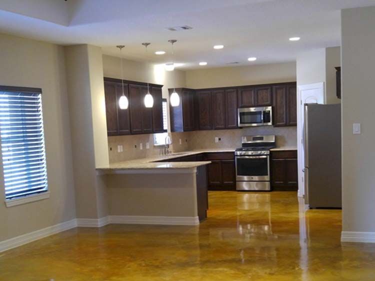 Open-plan kitchen with dark cabinets, stainless steel appliances, and golden-toned floor.