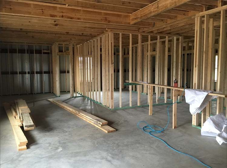 Interior of a building under construction, wooden framing, concrete floor, lumber, unfinished.
