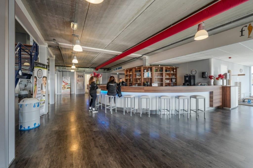 Bar met gasten. Grijze vloer, witte bar en rode pijp.