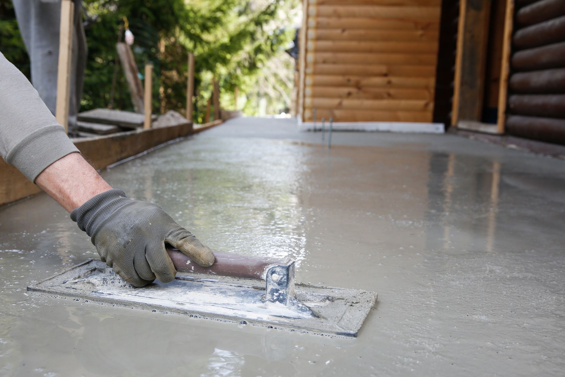 A man is using a trowel to spread concrete on a sidewalk.