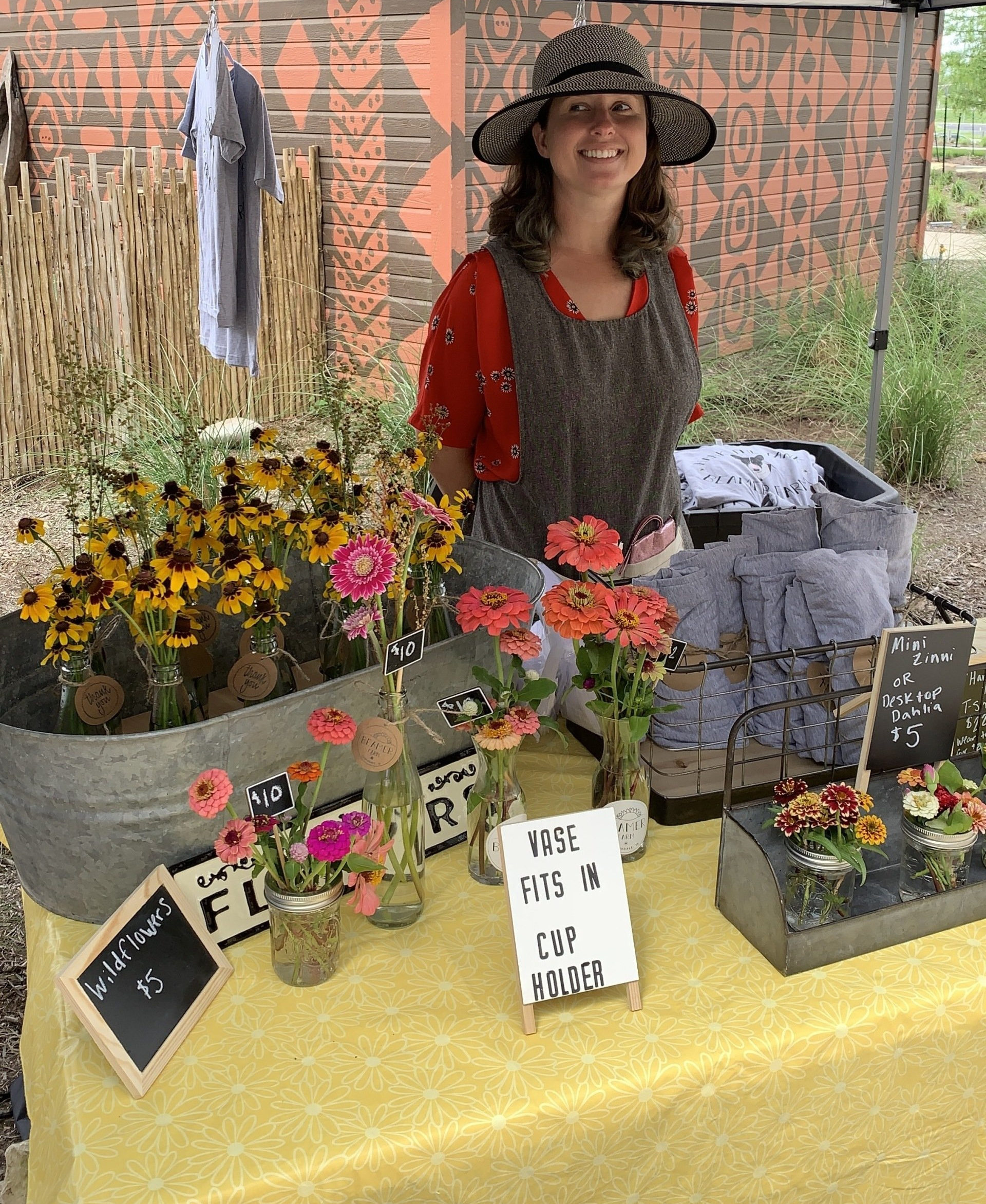 A woman is standing behind a table with flowers on it.