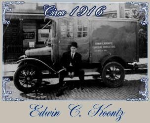 Man seated by a hearse, circa 1916. Vehicle with text 