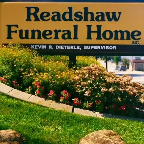 Readshaw Funeral Home sign with landscaping and street in background.