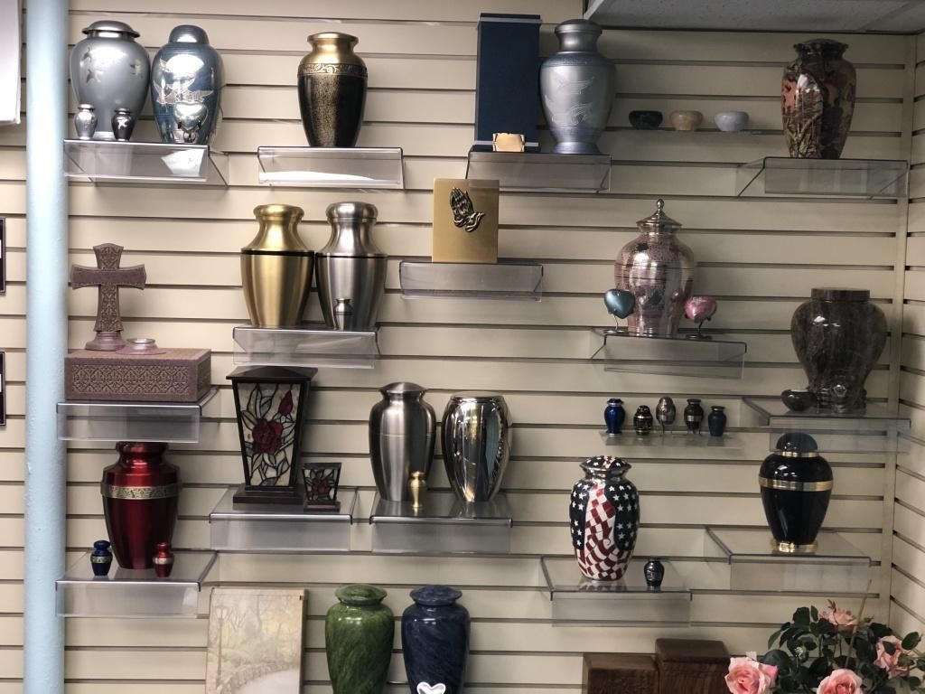 Display of various cremation urns on shelves in a retail setting.