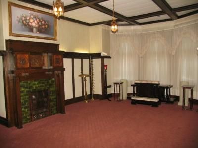 Formal room with fireplace, floral art, wood paneling, ornate lamps, and red carpet.