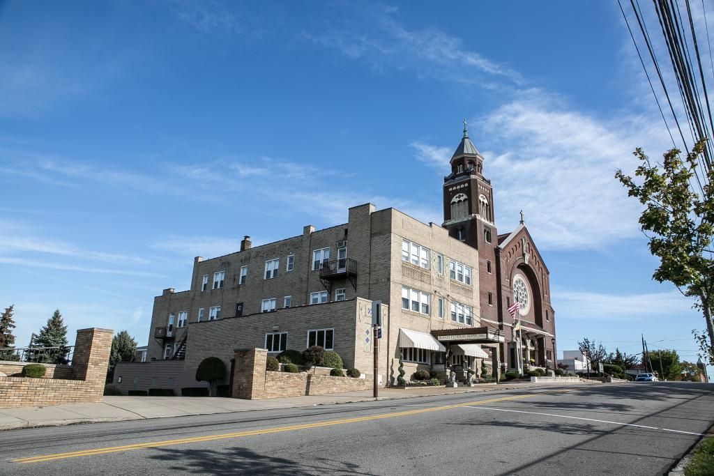 Church building with a tall tower and a large, stained glass window under a clear blue sky.
