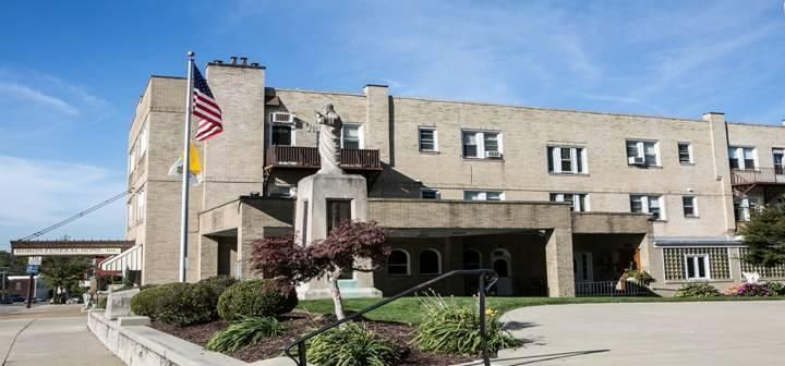 A beige building with a flag and a statue in front on a sunny day.