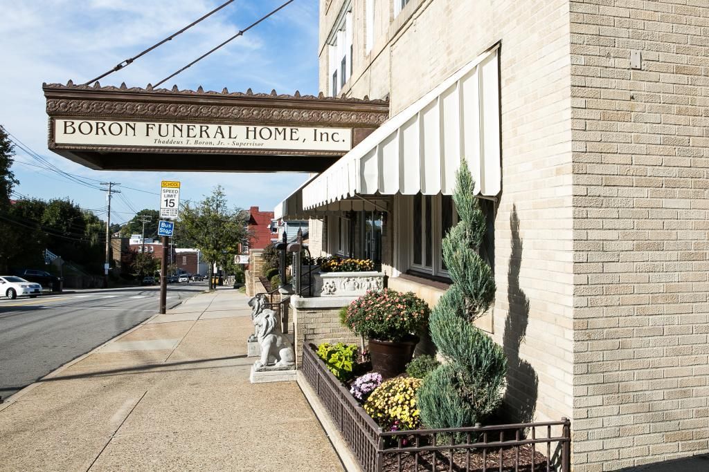 Boron Funeral Home entrance with awning, sign, brick wall, sidewalk, and street.