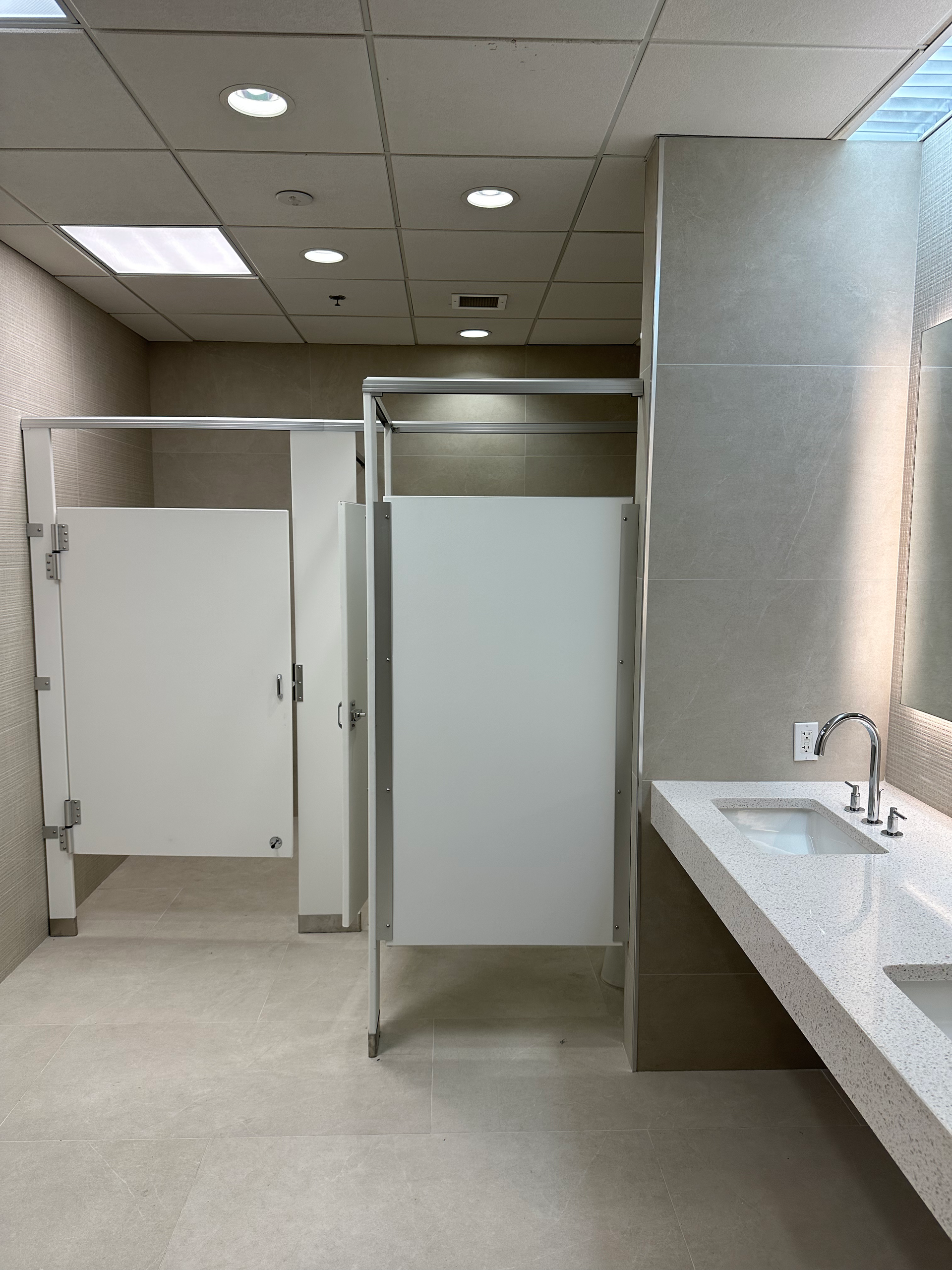 A bathroom with white stalls and a sink
