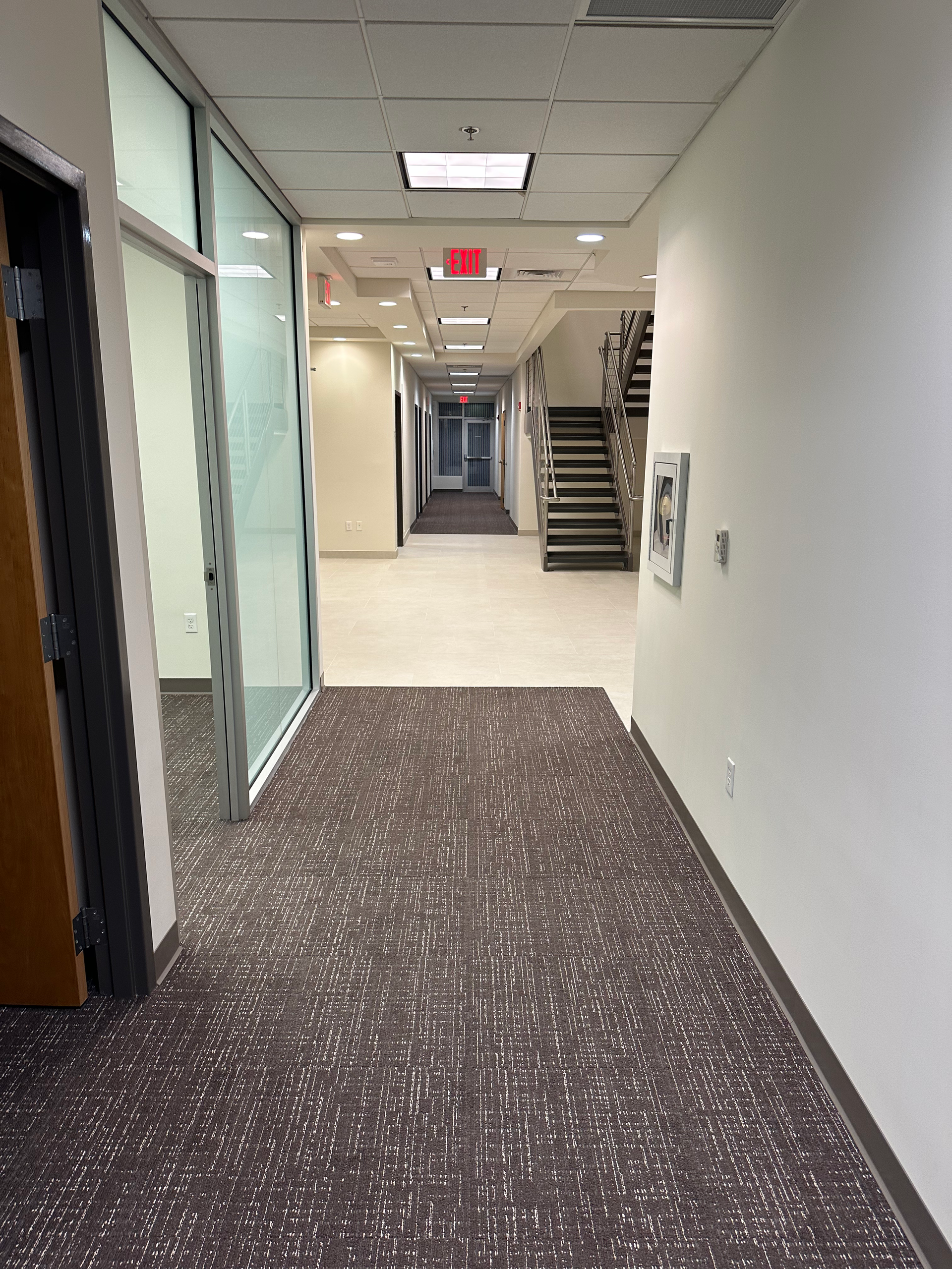 A long hallway with stairs and a fire extinguisher on the wall.