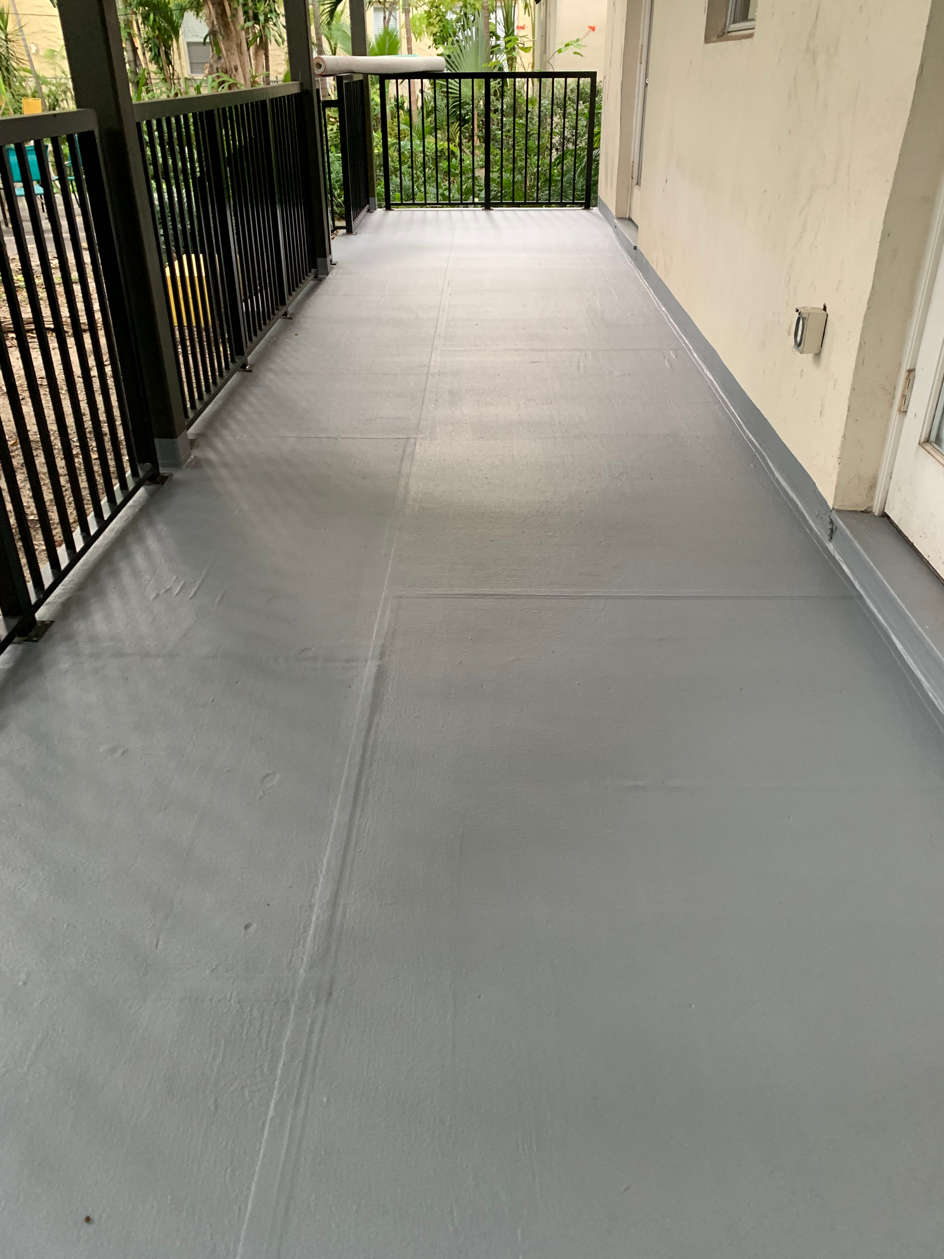 A gray walkway leading to a balcony with a black railing.