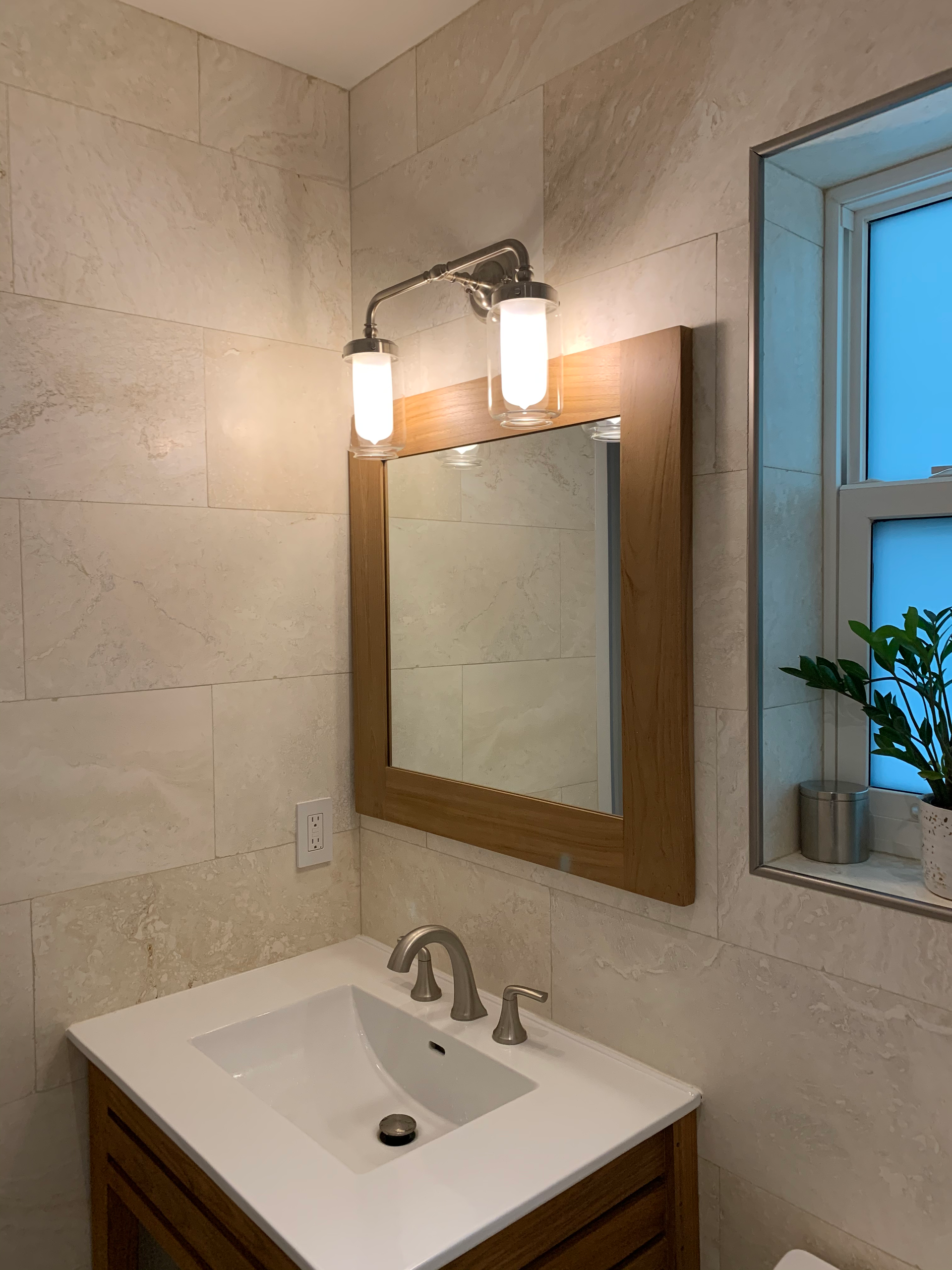 A bathroom with a sink , mirror and window