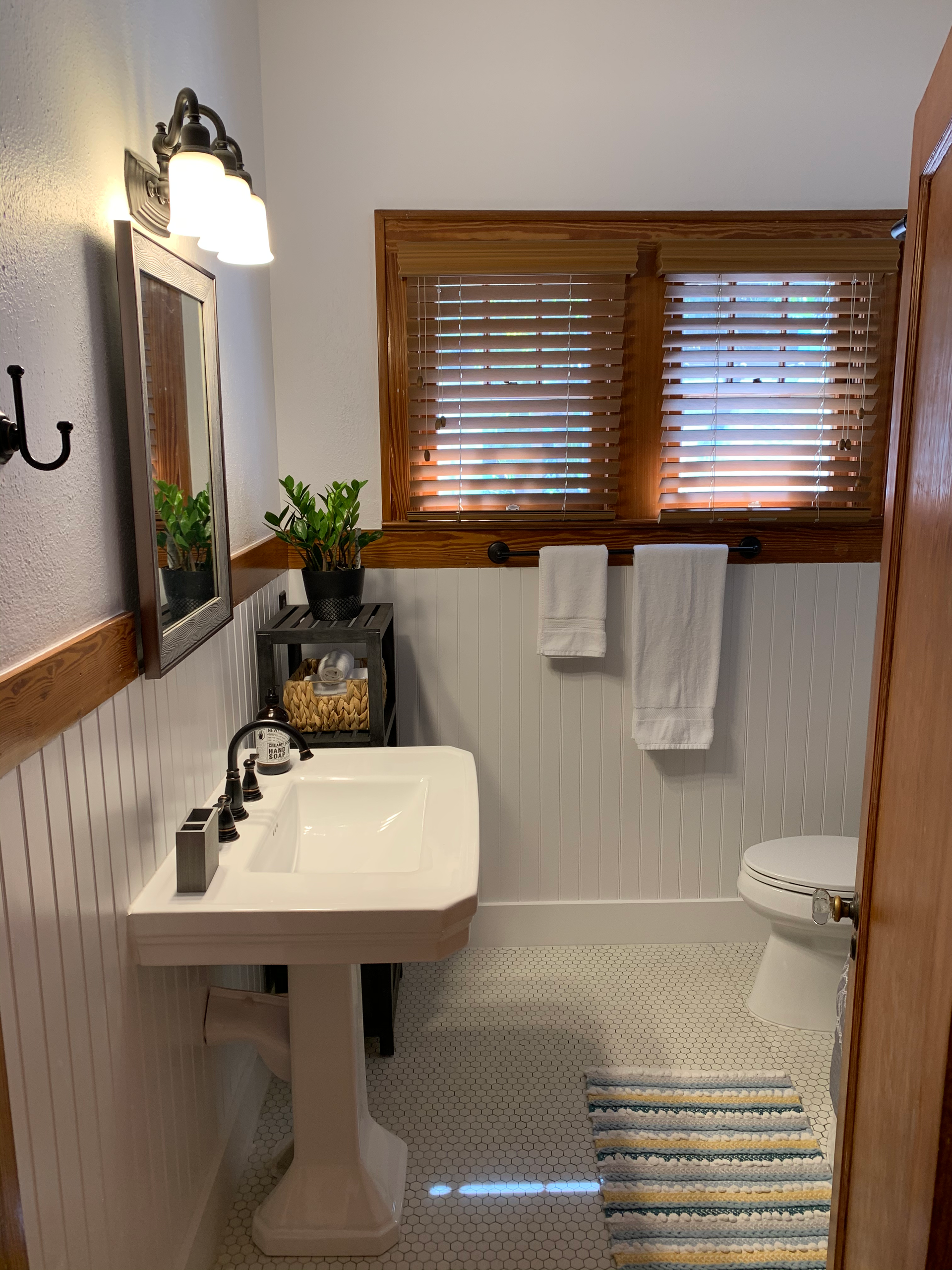 A bathroom with a sink , toilet , mirror and window.