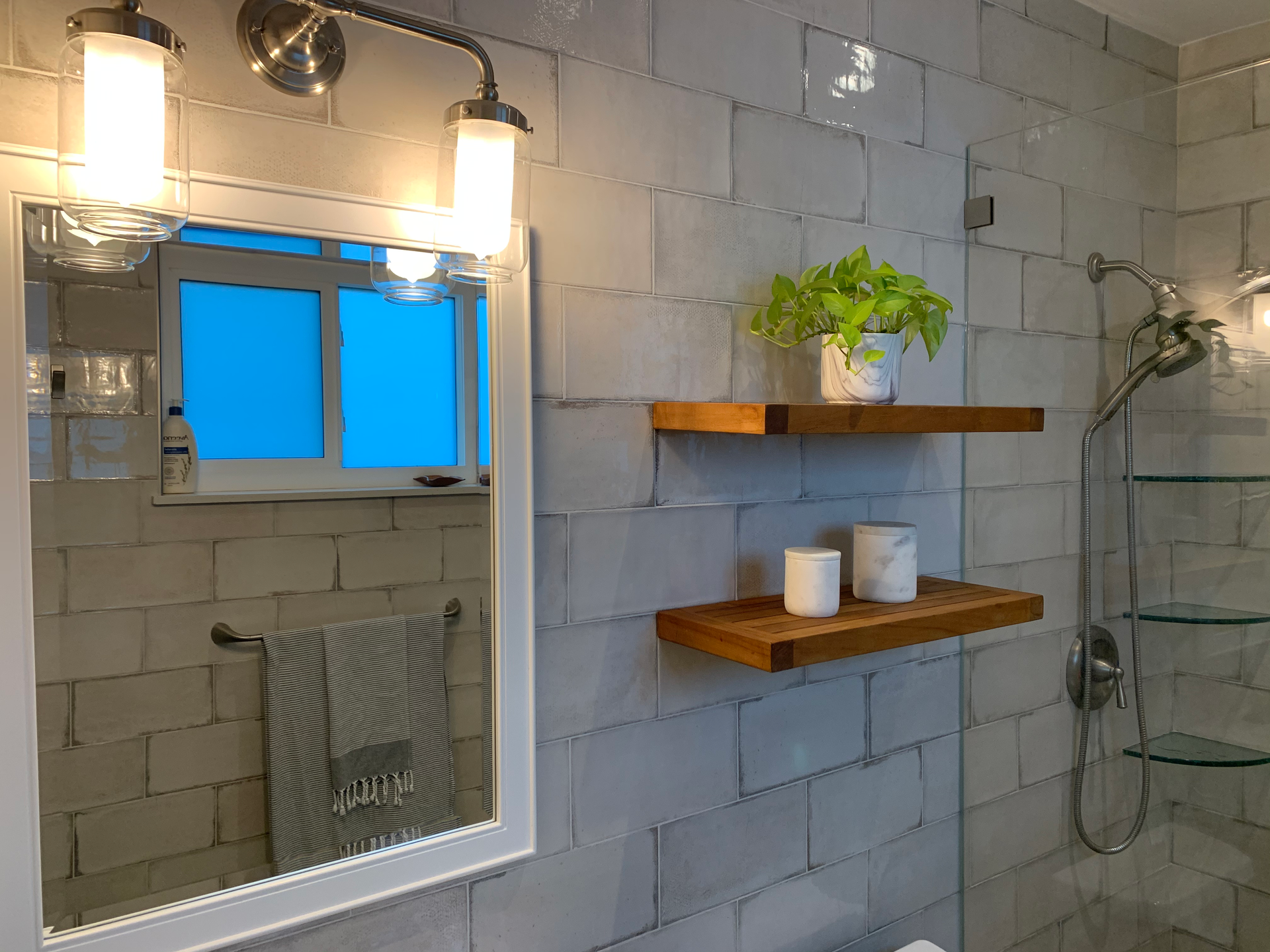 A bathroom with a mirror , shelves , and a shower.