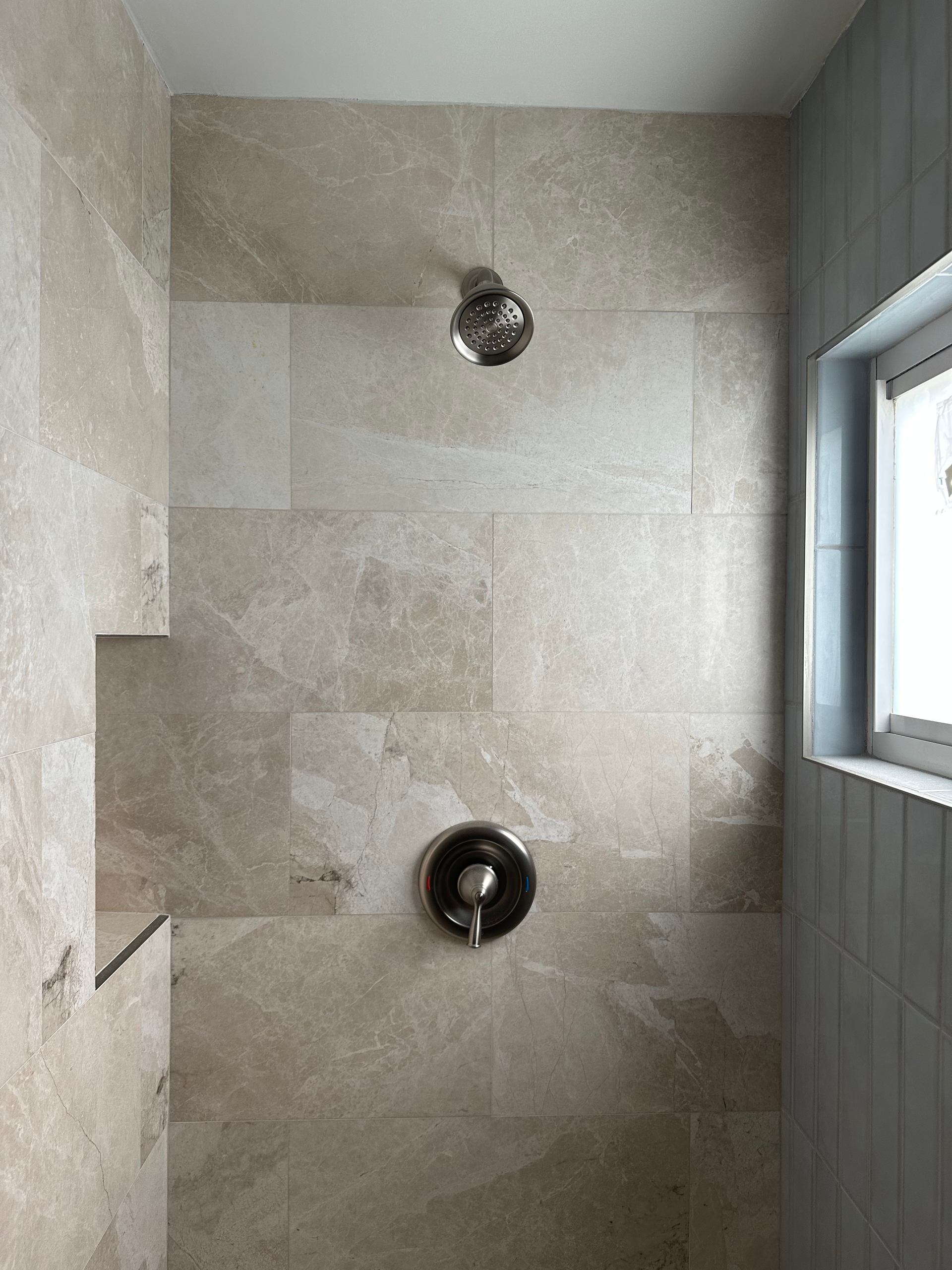 A bathroom with a shower head and a window.
