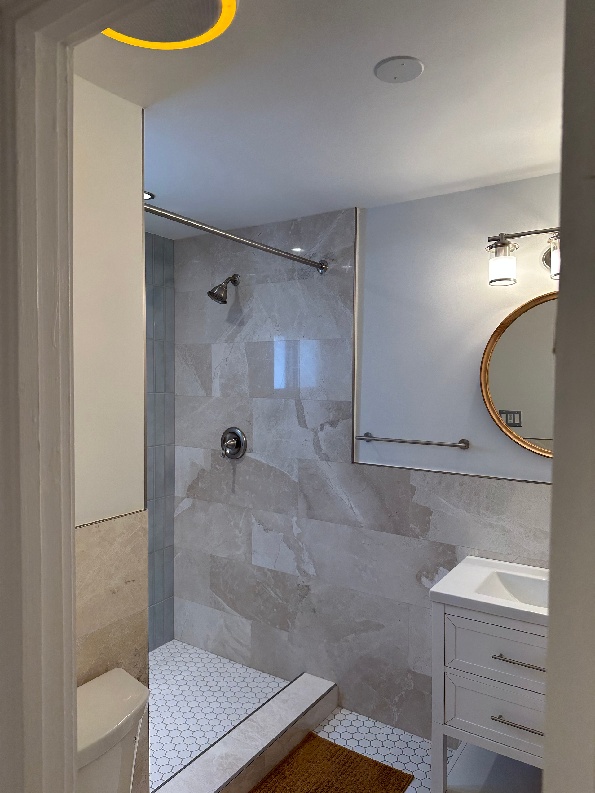 A bathroom with a walk in shower , sink and mirror.