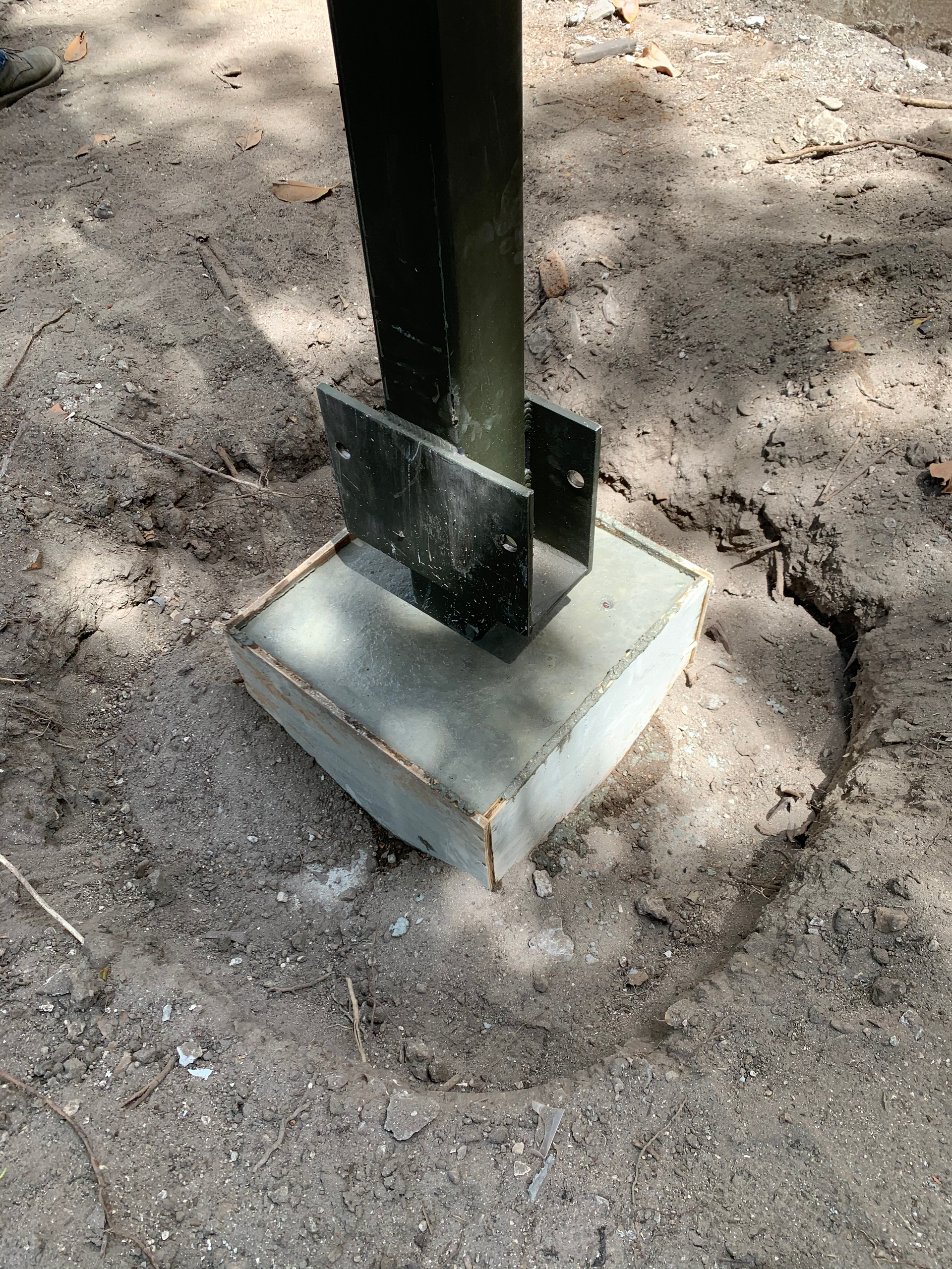 A metal pole is sitting on top of a concrete base.
