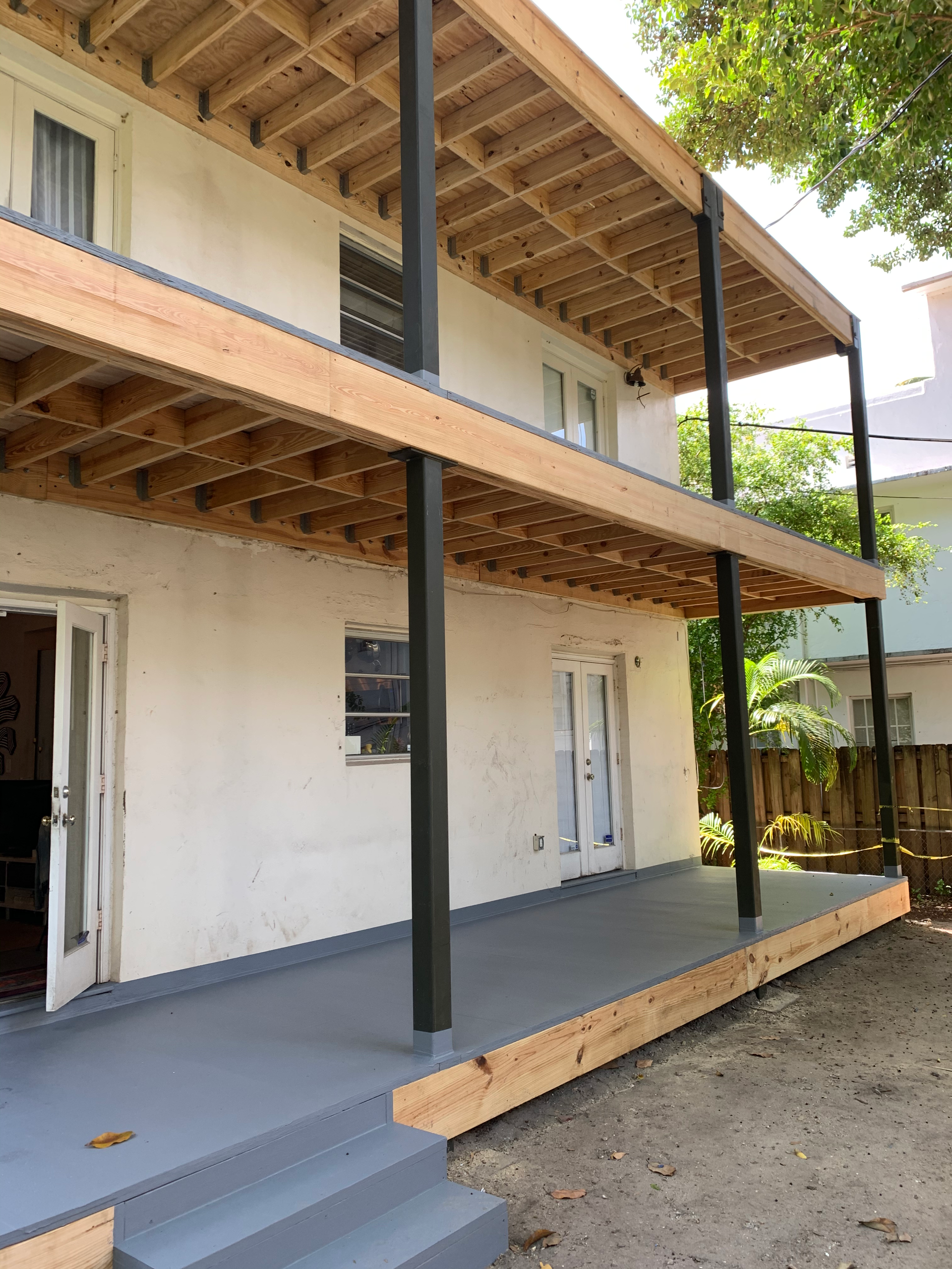 A white house with a wooden deck and stairs