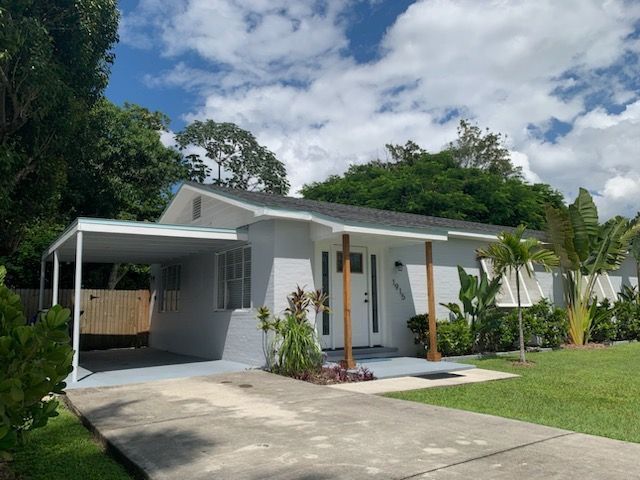 A white house with a canopy over the driveway