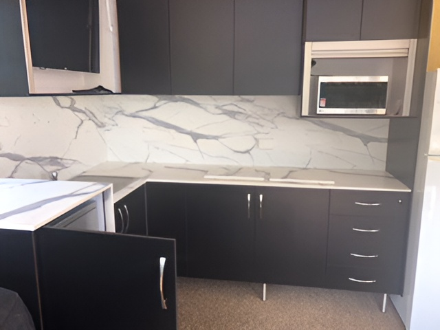A Kitchen With Black Cabinets and White Counter Tops — Mackay Cabinetmaking Service In Glenella, QLD