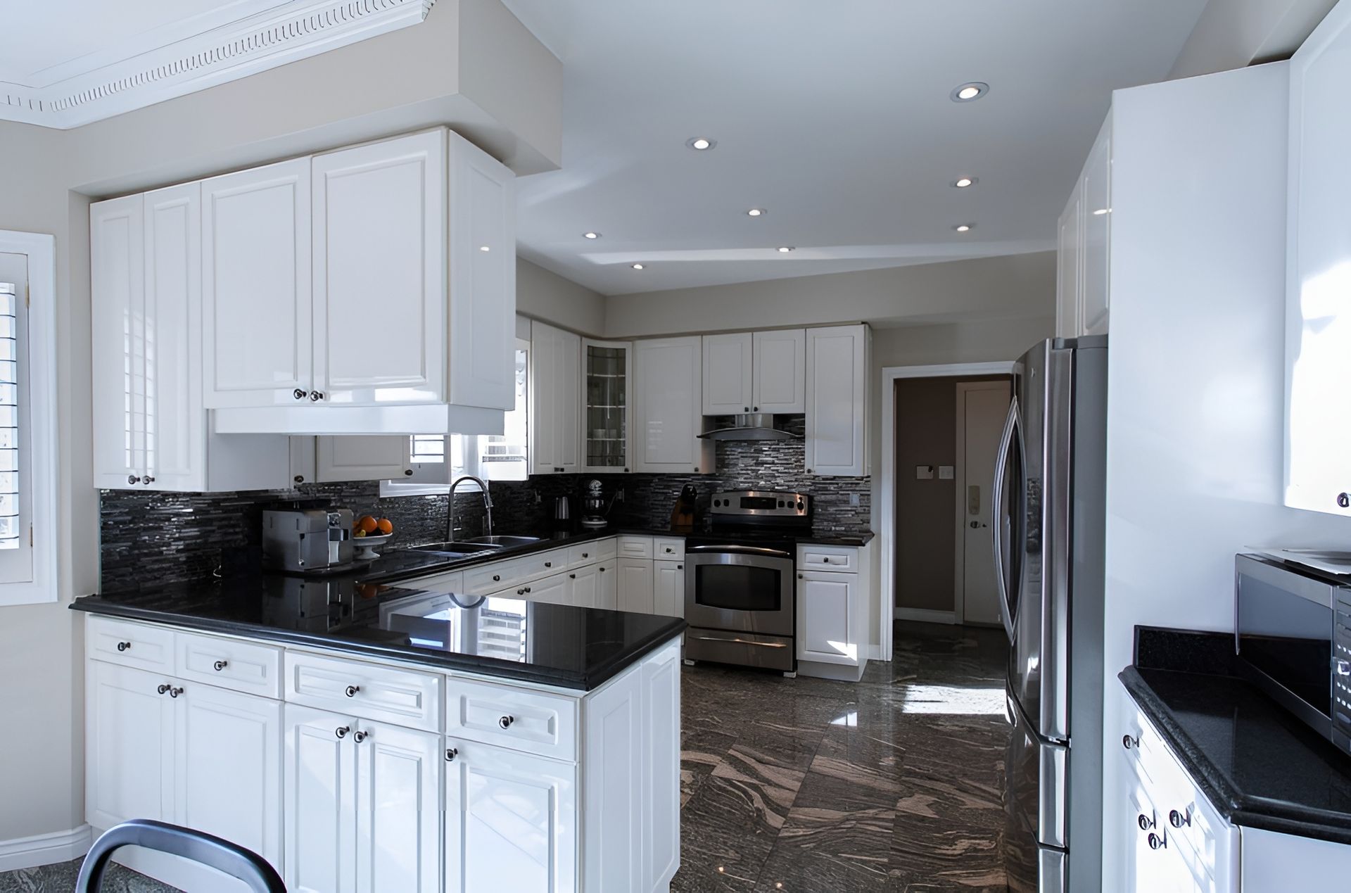 A Kitchen With White Cabinets and Black Counter Tops — Mackay Cabinetmaking Service In Glenella, QLD