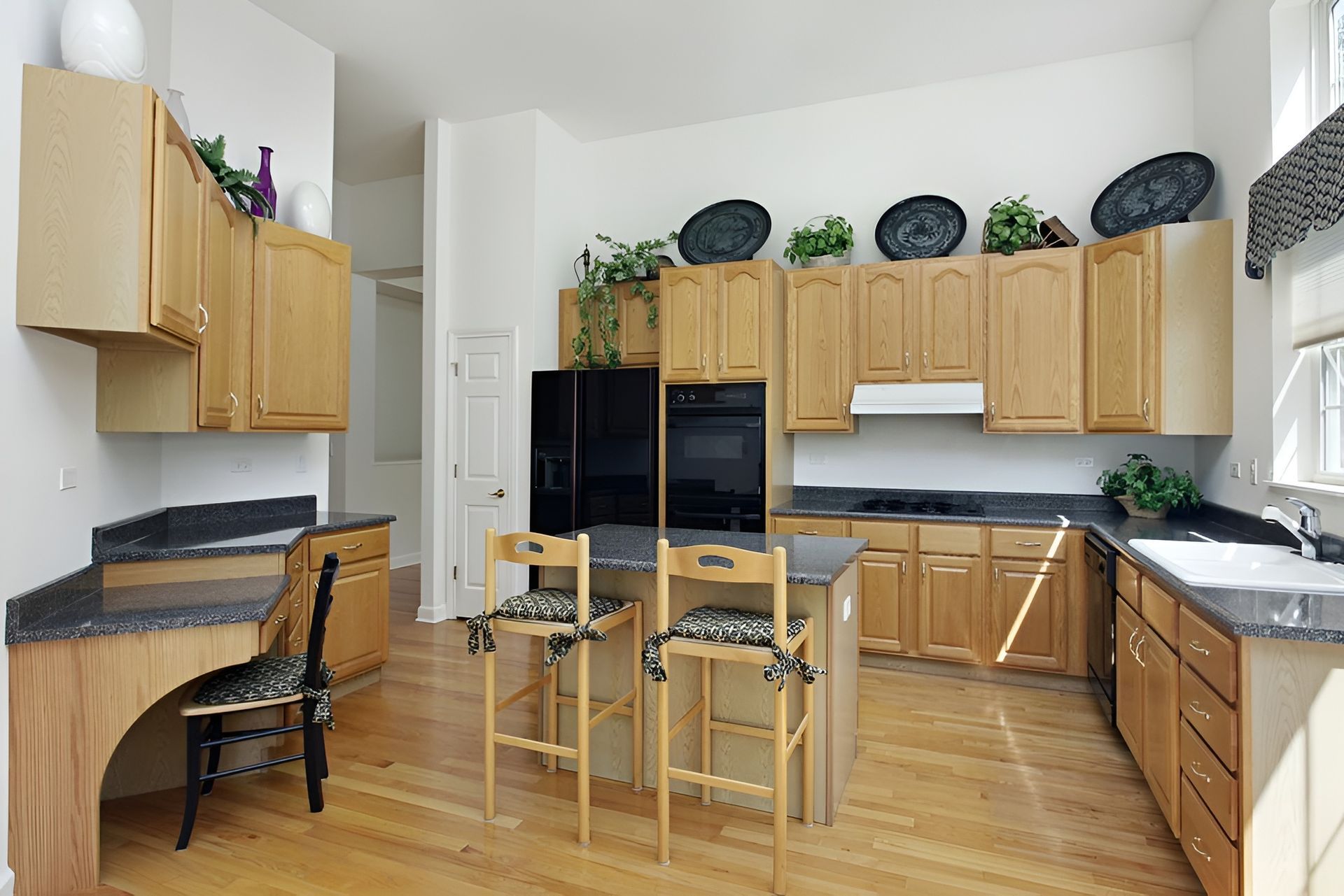 A Kitchen With Wooden Cabinets and Granite Counter Tops — Mackay Cabinetmaking Service In Glenella, QLD