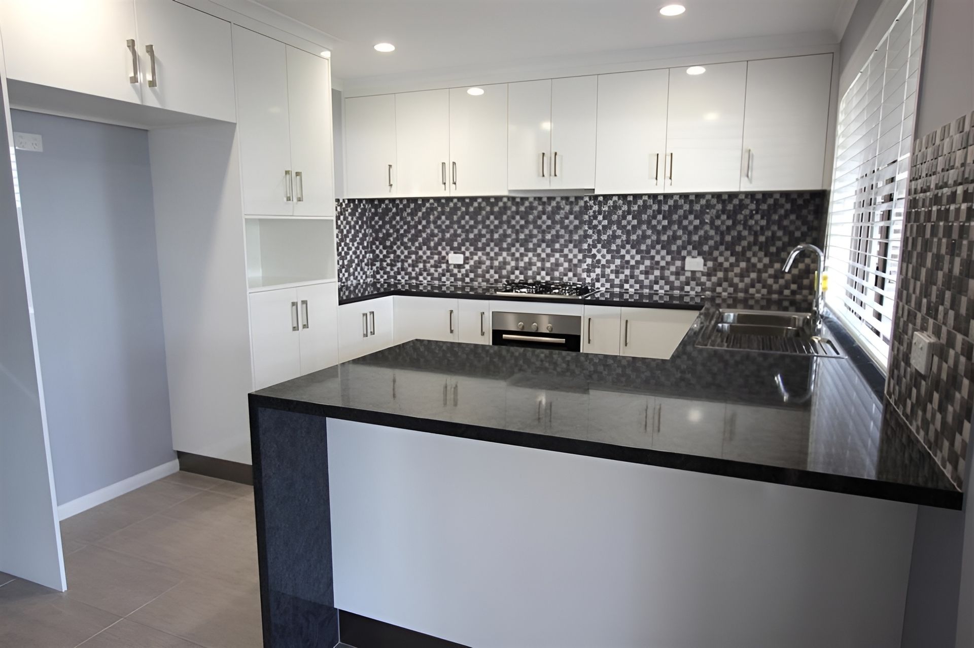 An Empty Kitchen With White Cabinets and Black Counter Tops — Mackay Cabinetmaking Service In Glenella, QLD