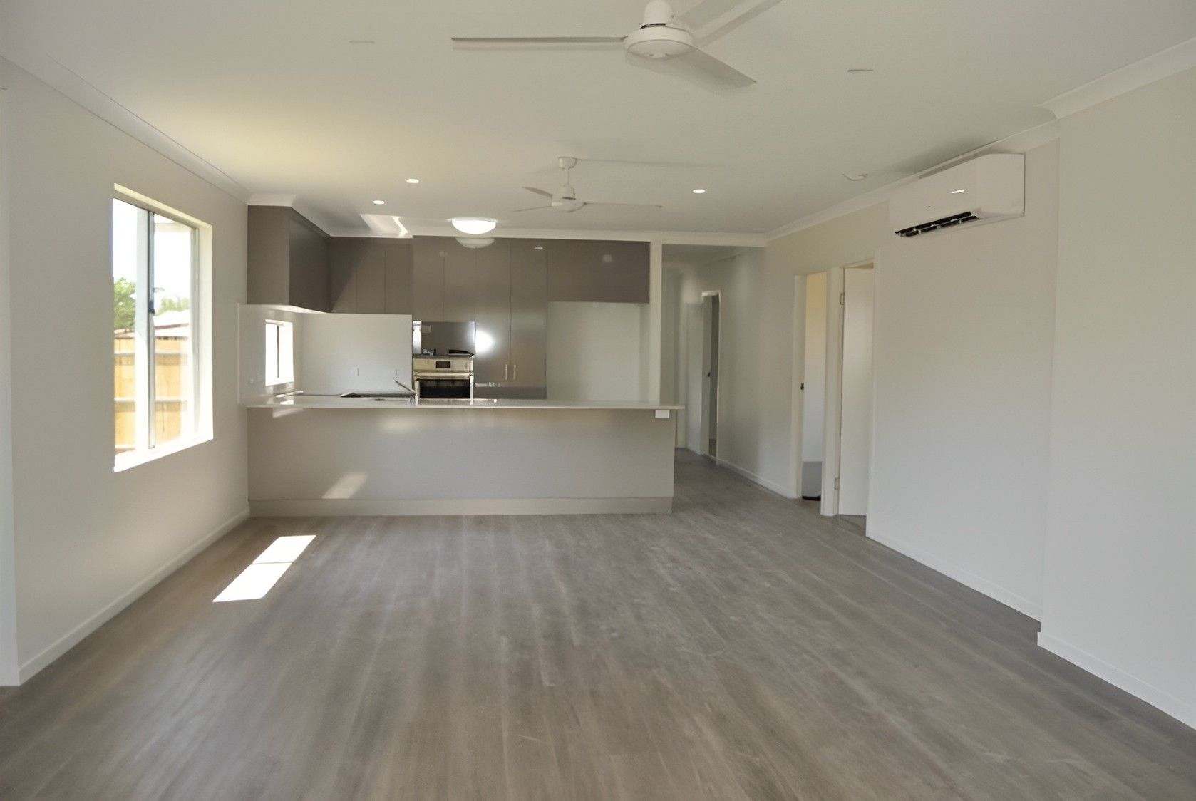 An Empty Living Room With a Kitchen and a Ceiling Fan — Mackay Cabinetmaking Service In Glenella, QLD