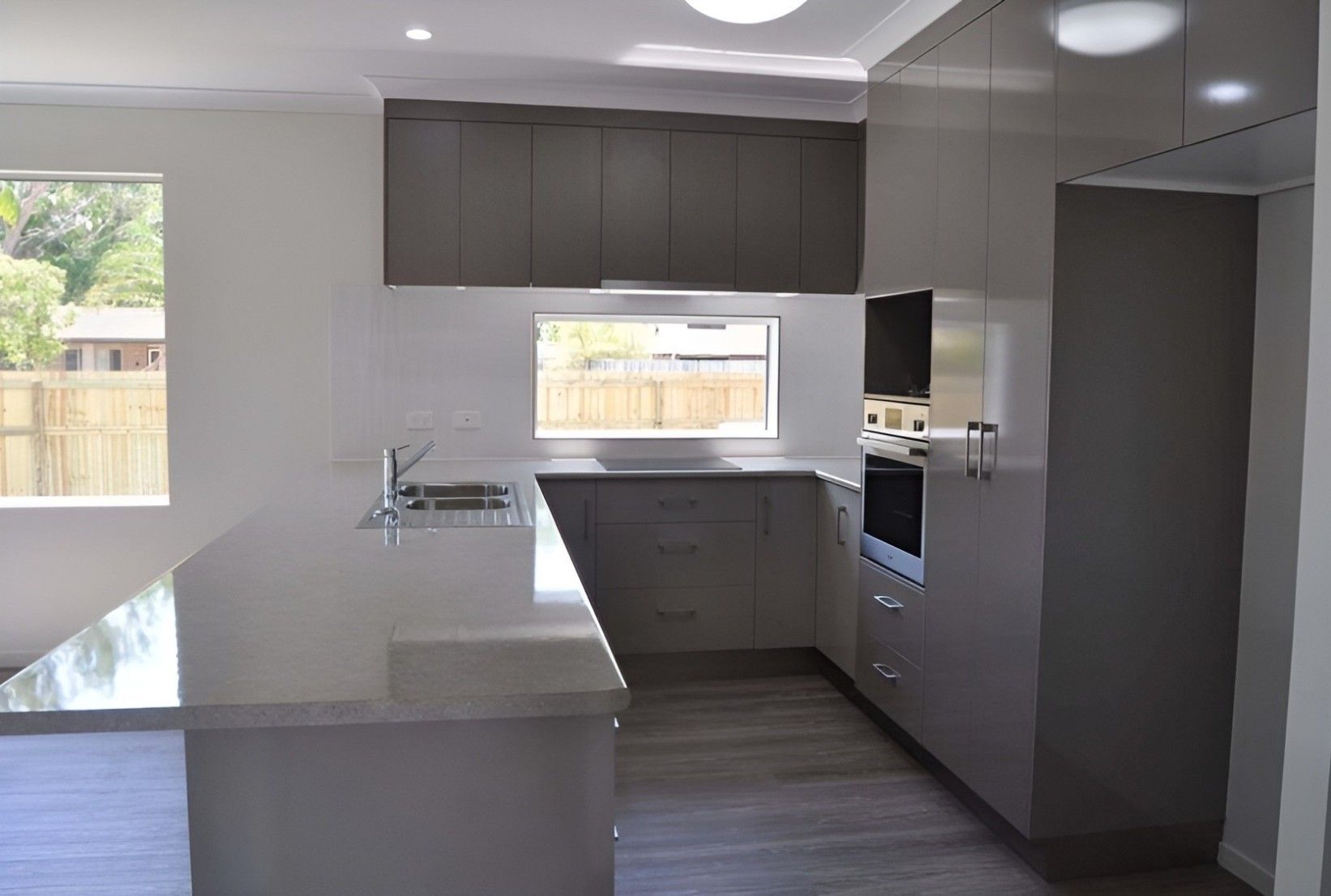 A Kitchen With Gray Cabinets, a Sink, and a Window — Mackay Cabinetmaking Service In Glenella, QLD