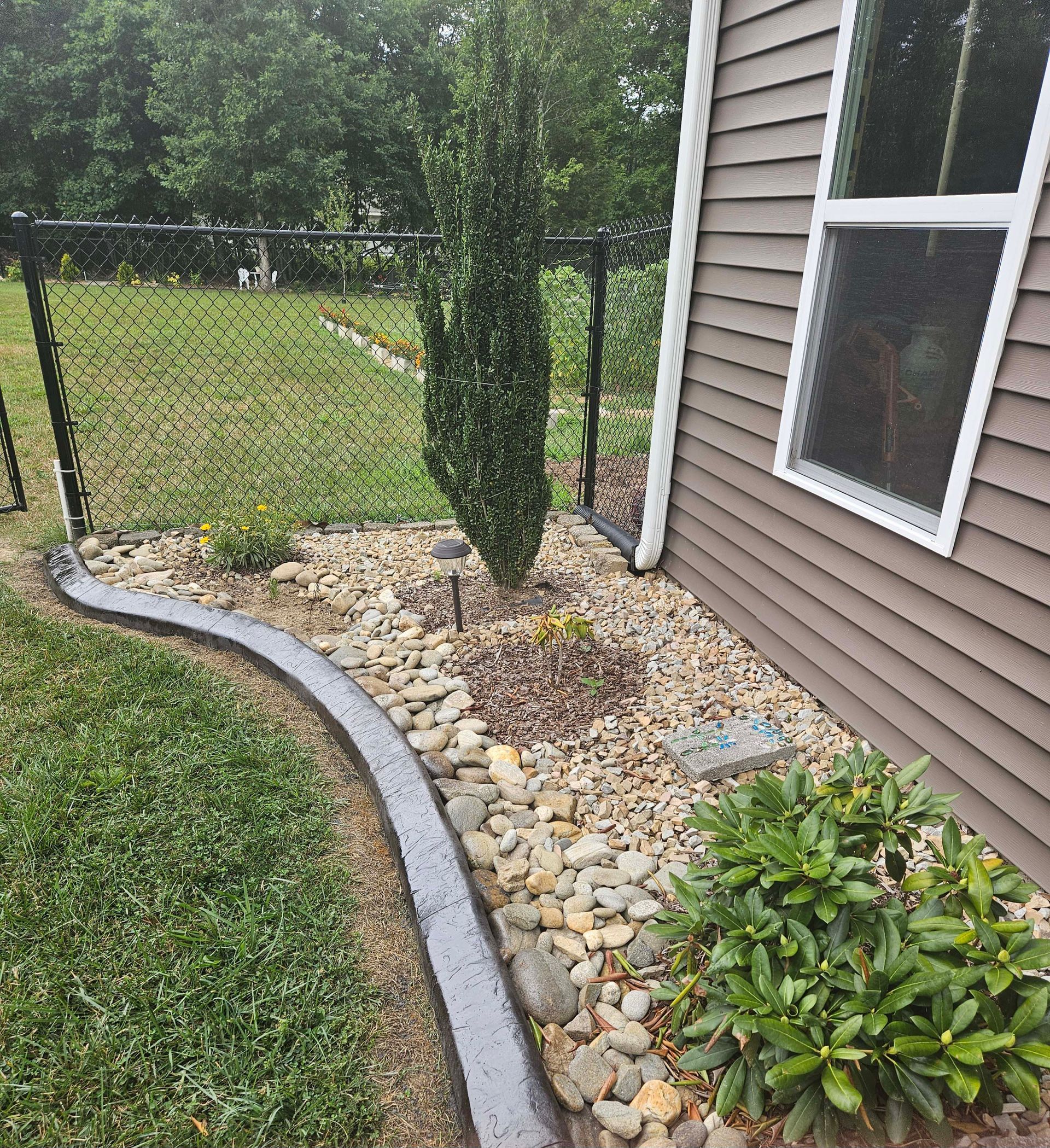 A house with a fence and a concrete curb in front of it.