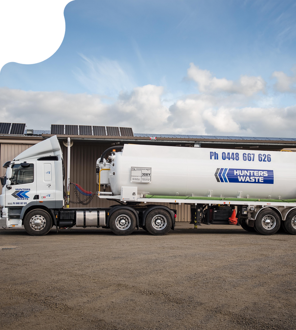White tanker truck parked outdoors under a partly cloudy sky. White tanker truck parked outdoors under a partly cloudy sky.