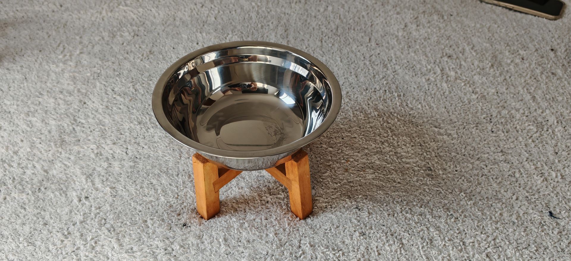 Un recipiente de acero inoxidable está sobre un soporte de madera sobre una alfombra.