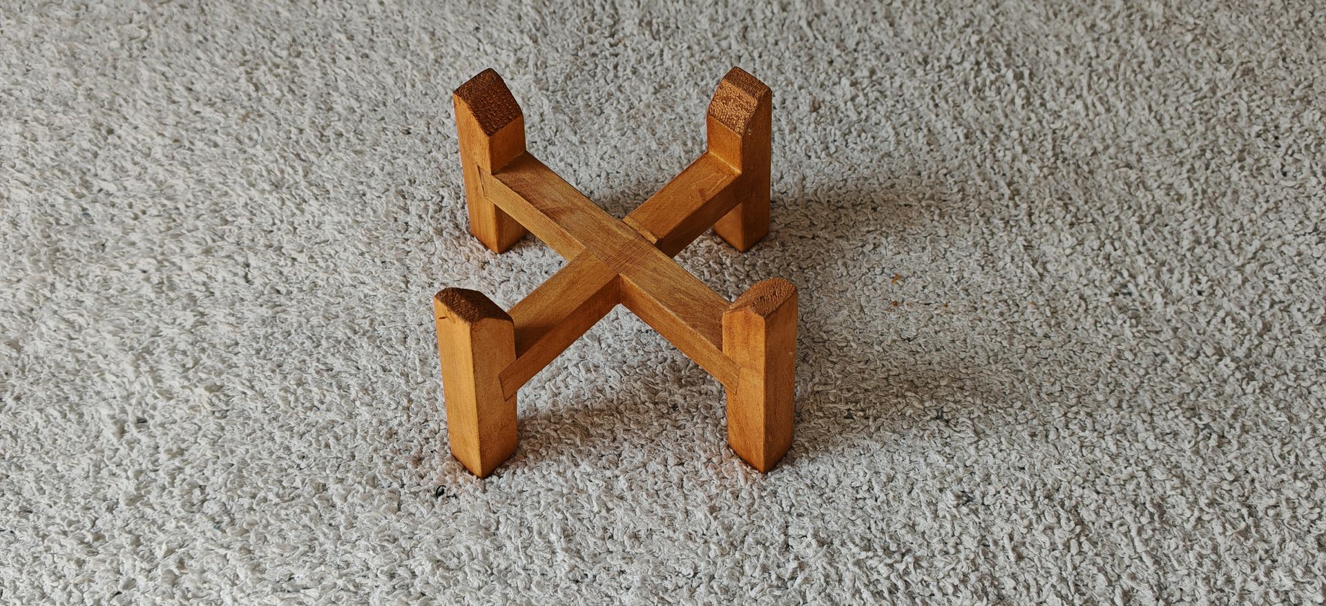 Un recipiente de acero inoxidable está sobre un soporte de madera sobre una alfombra.