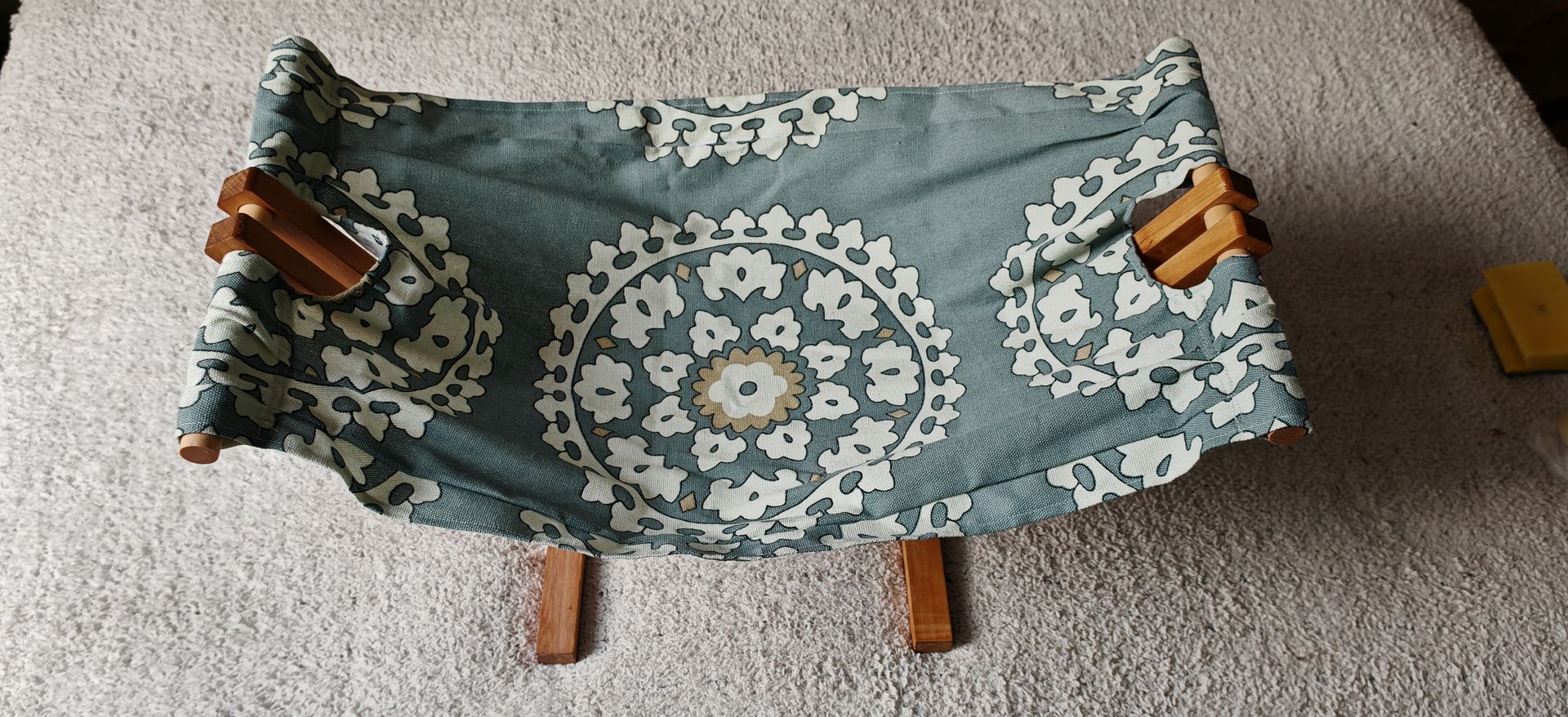 Una hamaca azul y blanca con patas de madera está colocada sobre una alfombra.