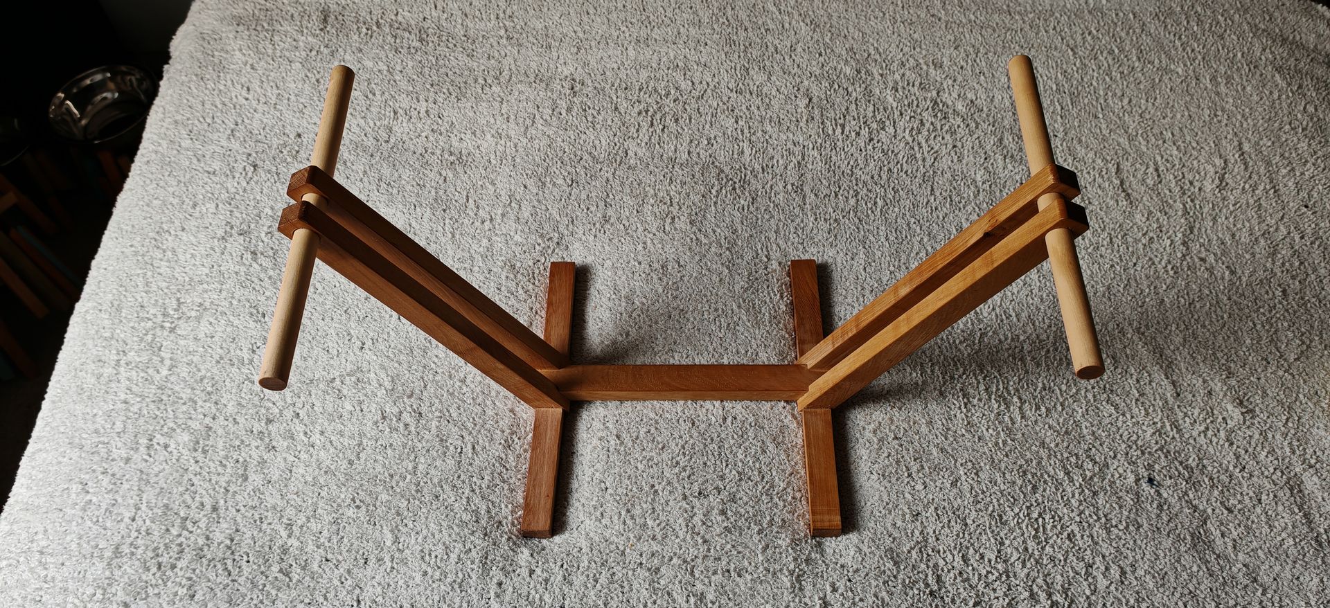 Una hamaca azul y blanca con patas de madera está colocada sobre una alfombra.